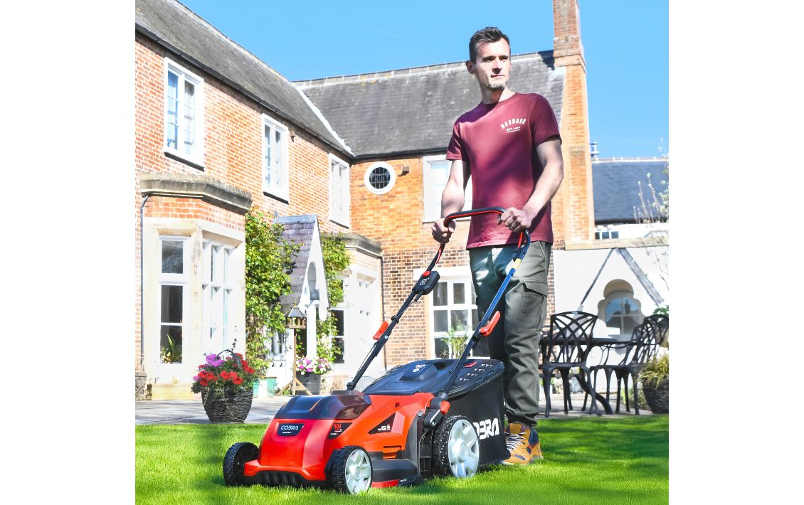 A man mowing a lawn with a Cobra lawn mower