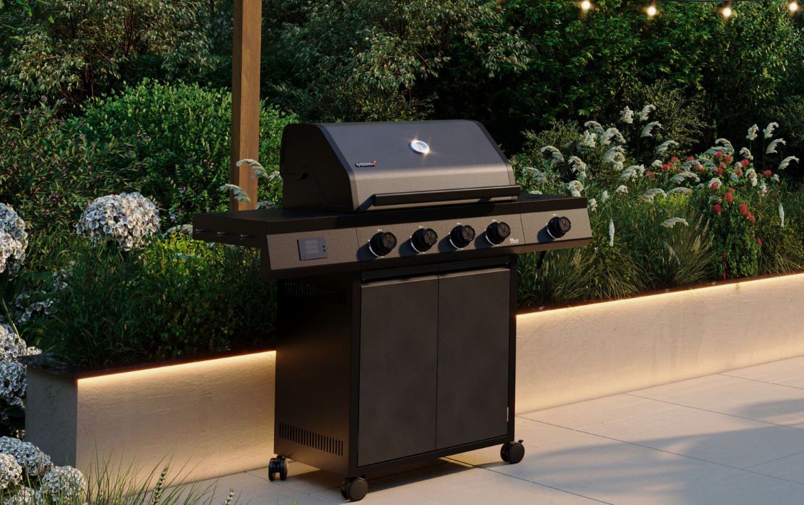 Dark grey barbecue on a patio in front of a garden