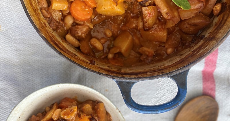 Rainy day beef, vegetable and bean stew from above with a bowl and a wooden spoon