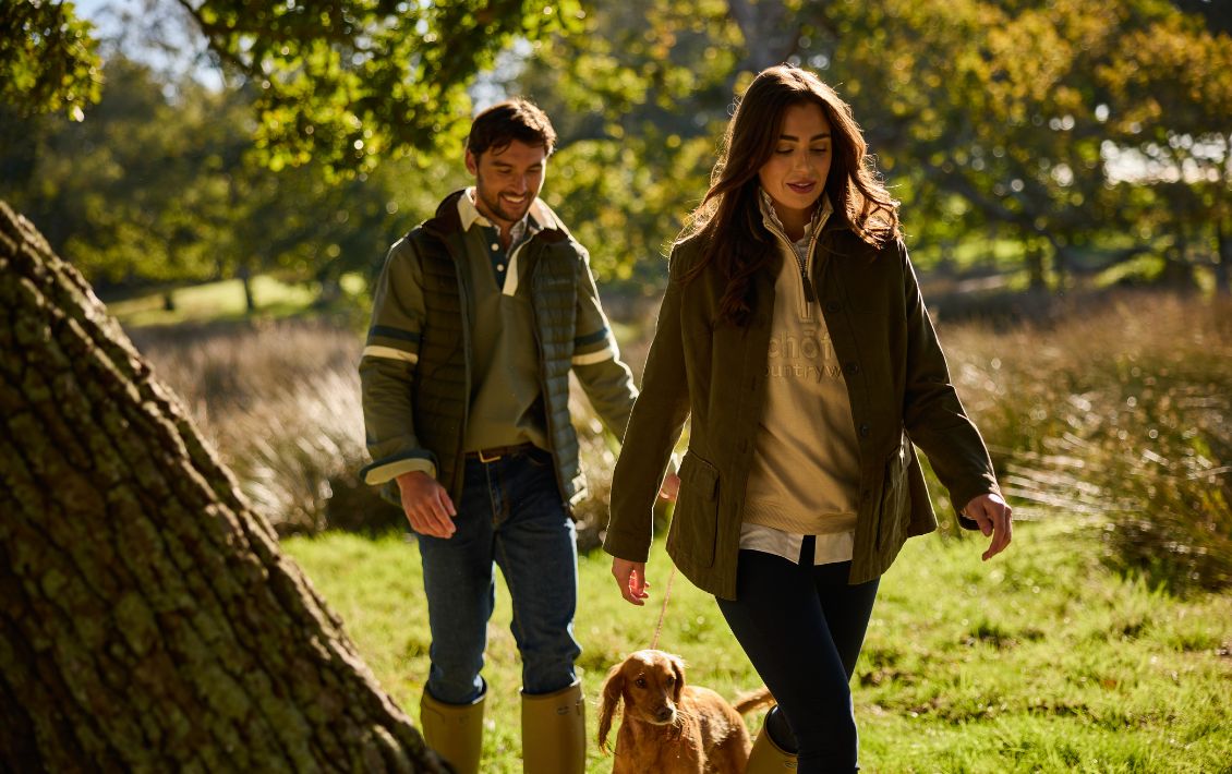 A man and woman wearing Schöffel clothing and walking a cocker spaniel 