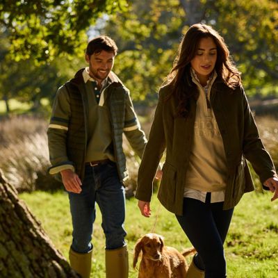 A man and woman wearing Schöffel clothing and walking a cocker spaniel 